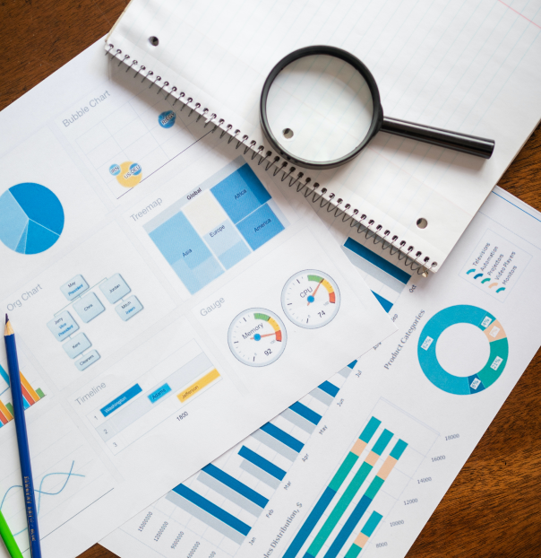 A desk covered with graphs and a magnifying glass